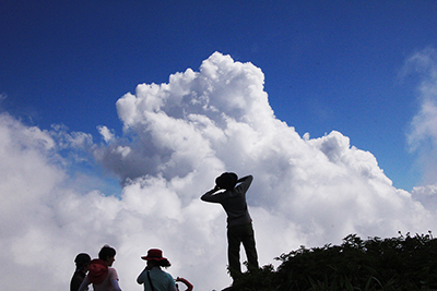 黒ボッコ岩で入道雲に向かって写真を撮っている人の写真