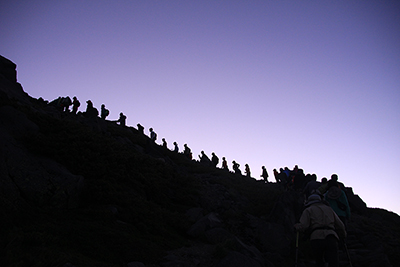 黎明のときに御前峰を目指して登る人の列のシルエットの写真