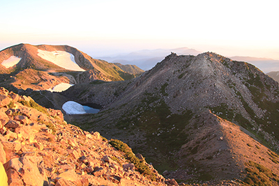 御前峰から見た日の出直後の剣ヶ峰と大汝峰の写真