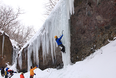 氷柱をアイスクライミングで登る人の写真
