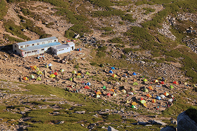 中岳から見た頂上山荘とテント場の写真
