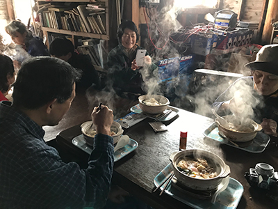 鍋割山荘で鍋焼きうどんを食べているメンバーの写真