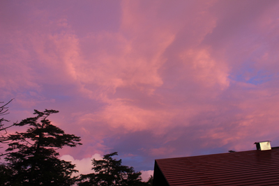 茜色に色づいた小屋上空の雲の写真