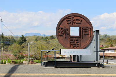 和同開珎のモニュメントがある和銅黒谷駅のホームと両神山の写真