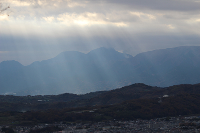 雲間からカーテンのように差し込む光と神山、駒ヶ岳の写真