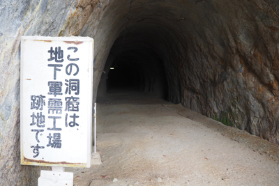 「この洞窟は地下軍需工場跡地ですと書かれた看板のある洞窟の写真」