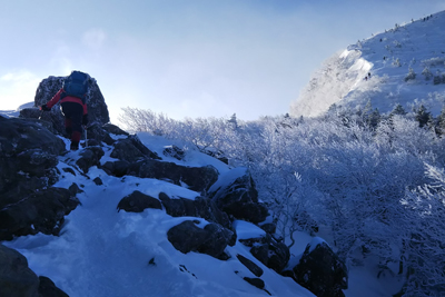 岩と雪のミックス帯を登っている写真