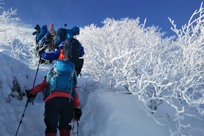 真っ白な樹氷と真っ青な空の下で登っている写真