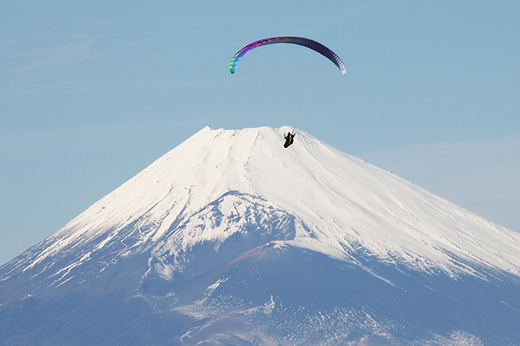 富士山を見ながら空を舞うパラグライダーの写真