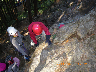 登山靴で岩を登るＭさんの写真