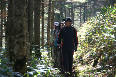 亀甲池付近の逆光の登山道を歩いている写真