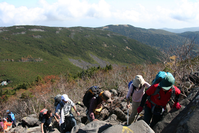 今日、歩いてきた双子山などを見下ろしながら岩場を登っている写真