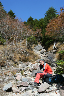 石ごろの登山道で座っているＹさんの写真