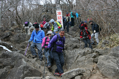 雪のない岩場を下っている写真