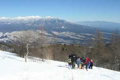 八ヶ岳と奥秩父を背に山頂直下を登っている写真