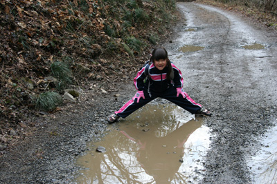 林道の水たまりを足を広げて渡ろうとしているＫちゃんの写真