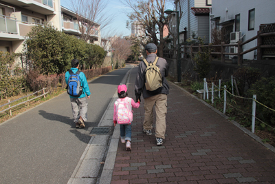 萱田地区公園に向けて歩道を手をつないで歩いているYさんとAちゃんの写真