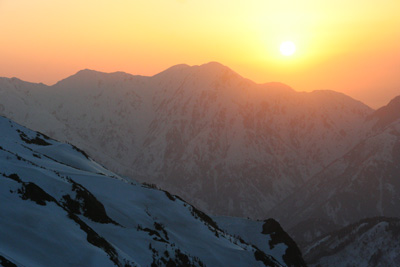毛勝三山の向こうに沈む夕日の写真