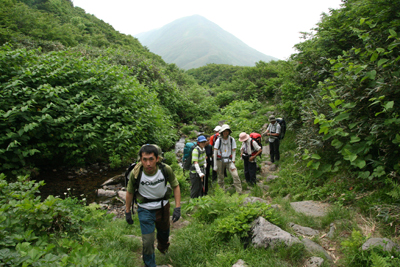 湯殿山を背に沢沿いの道を登っている写真