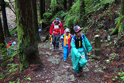 雨具を着て登山道を歩いている写真