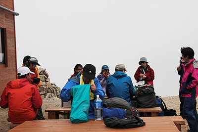 薬師岳山荘のベンチでくつろぐメンバーの写真
