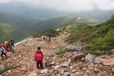 姿が見えるようになった遠くの山を見ながら下っている写真