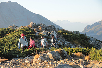 朝日を浴び、槍ヶ岳と雄山を背に登っている写真