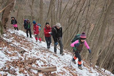 雪が多くなってきた登山道を登っている写真