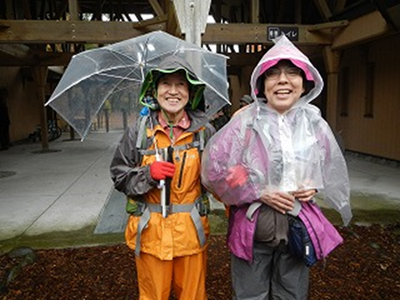 傘を差したＡさんと雨具を来たＮさんの写真