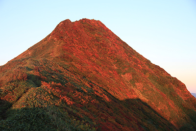 紅葉をさらに赤く染める朝日を受けたオジカ沢の頭の写真