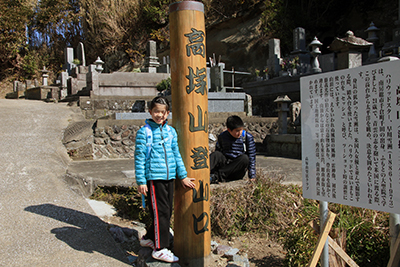大聖院の横にある登山口の標識にたったAちゃんと後ろに座っているM君の写真
