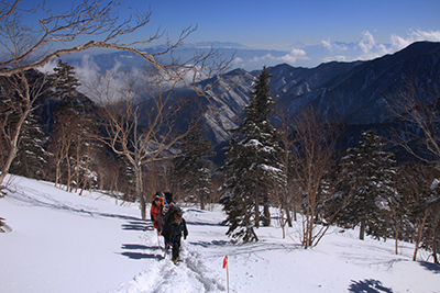 富士山や八ヶ岳方面を背に合戦の頭に向けて登っている写真