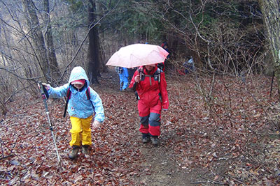 広い登山道を登るＫちゃんと傘を差して歩くＦさんの写真