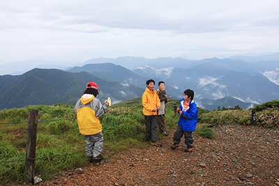 見晴らしの良い山頂でいろんな遊びを探す子どもたちの写真