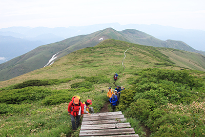 平標山と苗場山を背に登っている写真