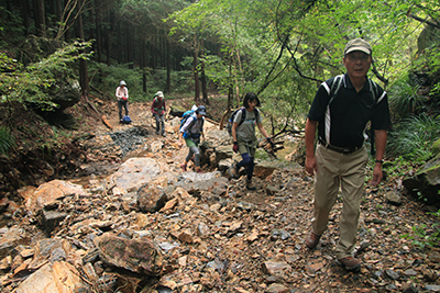 激しい雨で所々えぐられている登山道を歩いている写真
