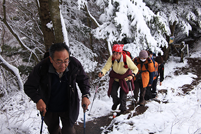 周囲に3cm程度積雪のある登山道を登っている写真