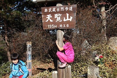 天覧山の標識の木に抱きついているＫちゃんの写真