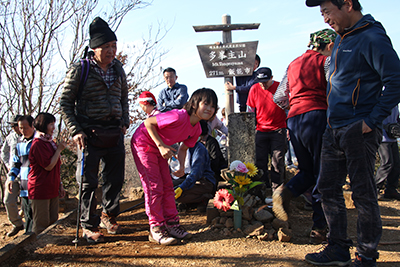 山頂標識の前のお墓の横でポーズを撮るＫちゃんの写真