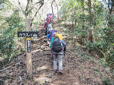 Iさんが撮影した「カラスバ山」と書かれた標識の横を登っている写真