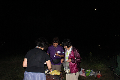 焼きそばを作っている女性陣と月の写真