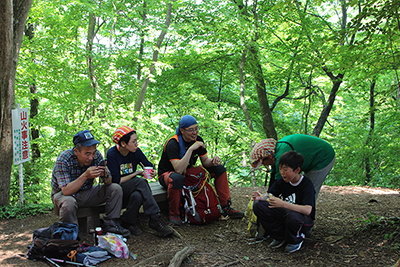 緑に囲まれた高水山山頂で昼食中の写真