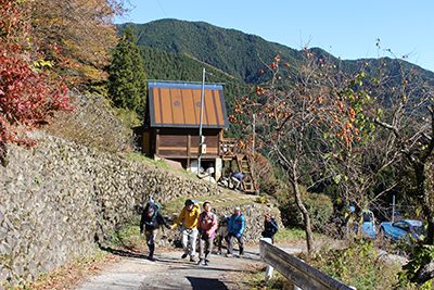 小さな山小屋を背に道路を上っている写真