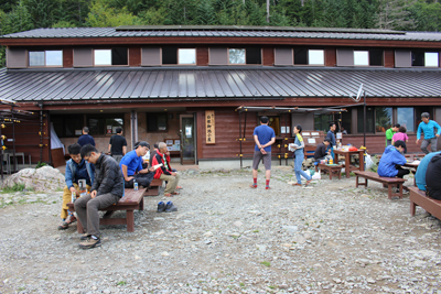 白根御池小屋とその前でくつろぐ人たちの写真