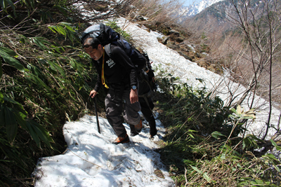 残雪の出てきた登山道を歩いている写真