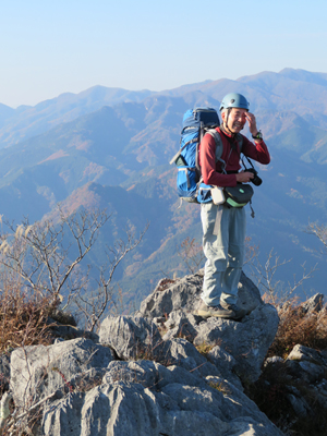 Mさんが撮影した遠くの山を背に岩場に立っているAさんの写真