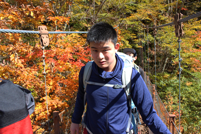 周囲の紅葉がきれいな二俣吊り橋を渡っているM君の写真