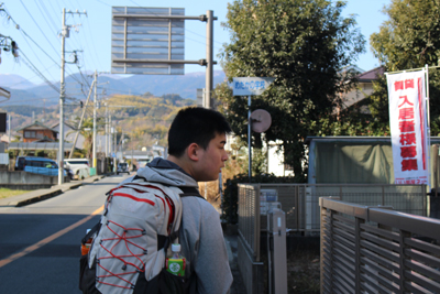 めだかの学校の案内板とその前に立つM君の写真