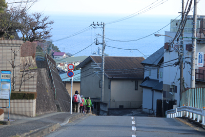 正面に海を見ながら歩道を歩いている写真