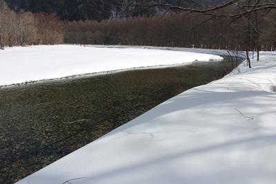 雪原と梓川の流れの写真